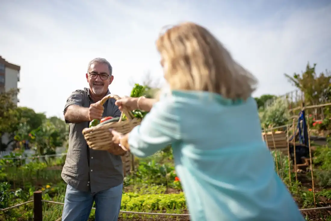 A volunteer handing vegetables to a neighbor in the garden