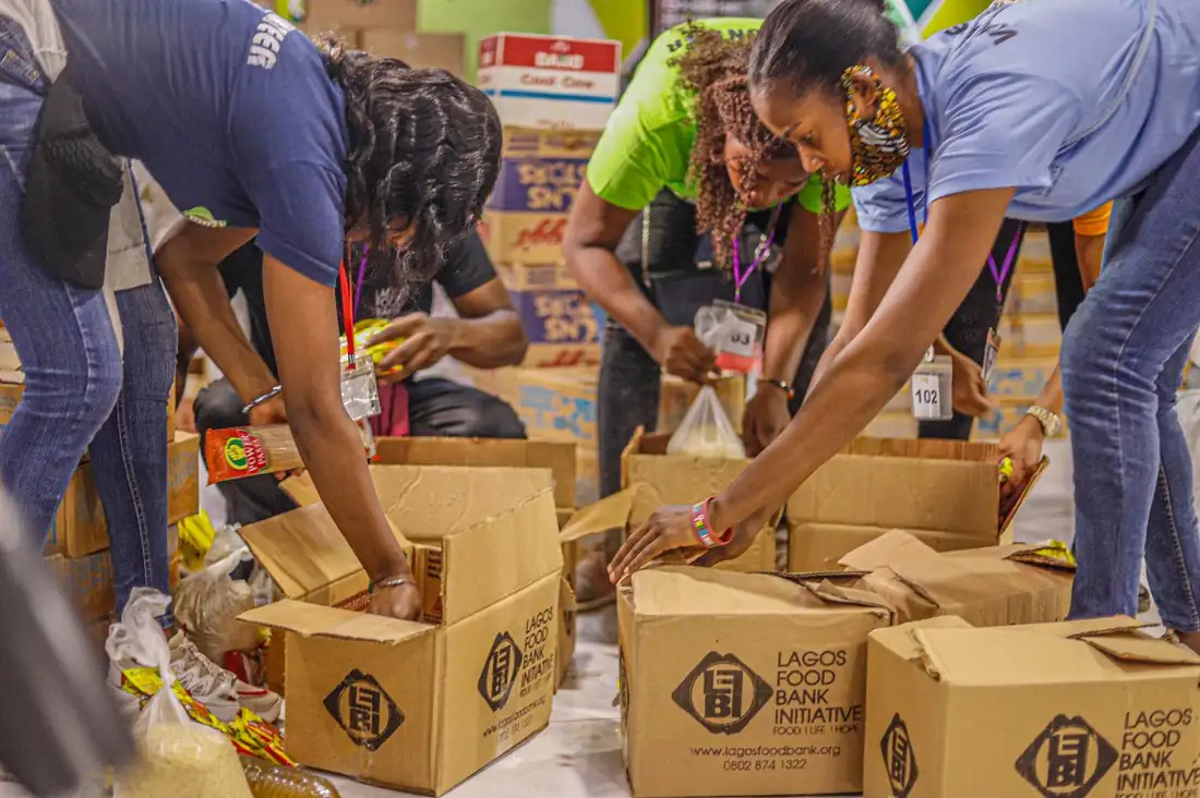 Many hands packing food boxes