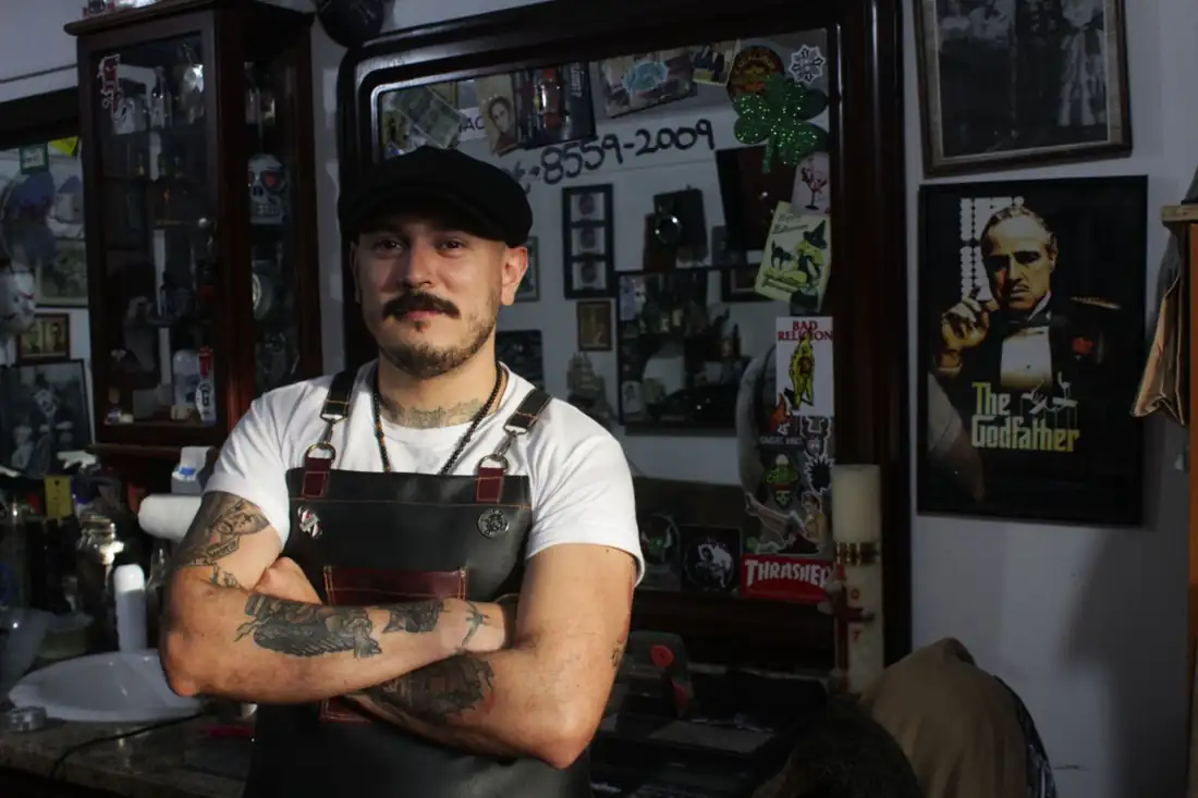 Rico, a barber, standing with arms crossed
