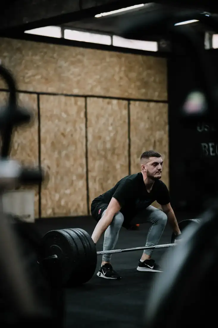Dex, a coach, deadlifting a loaded barbell