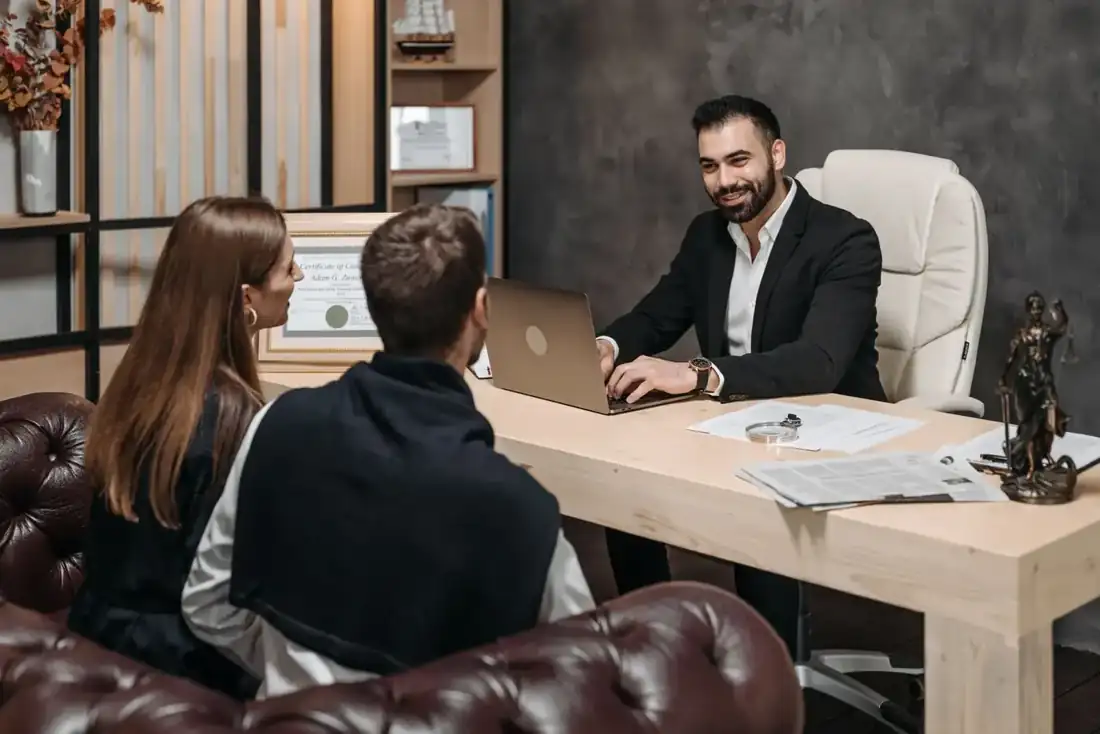 An attorney meeting with two clients at his desk