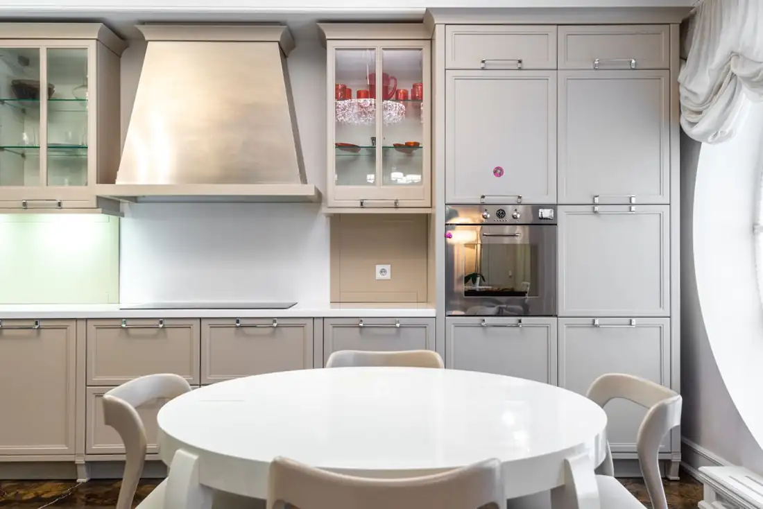 A bright white kitchen with a round dining table